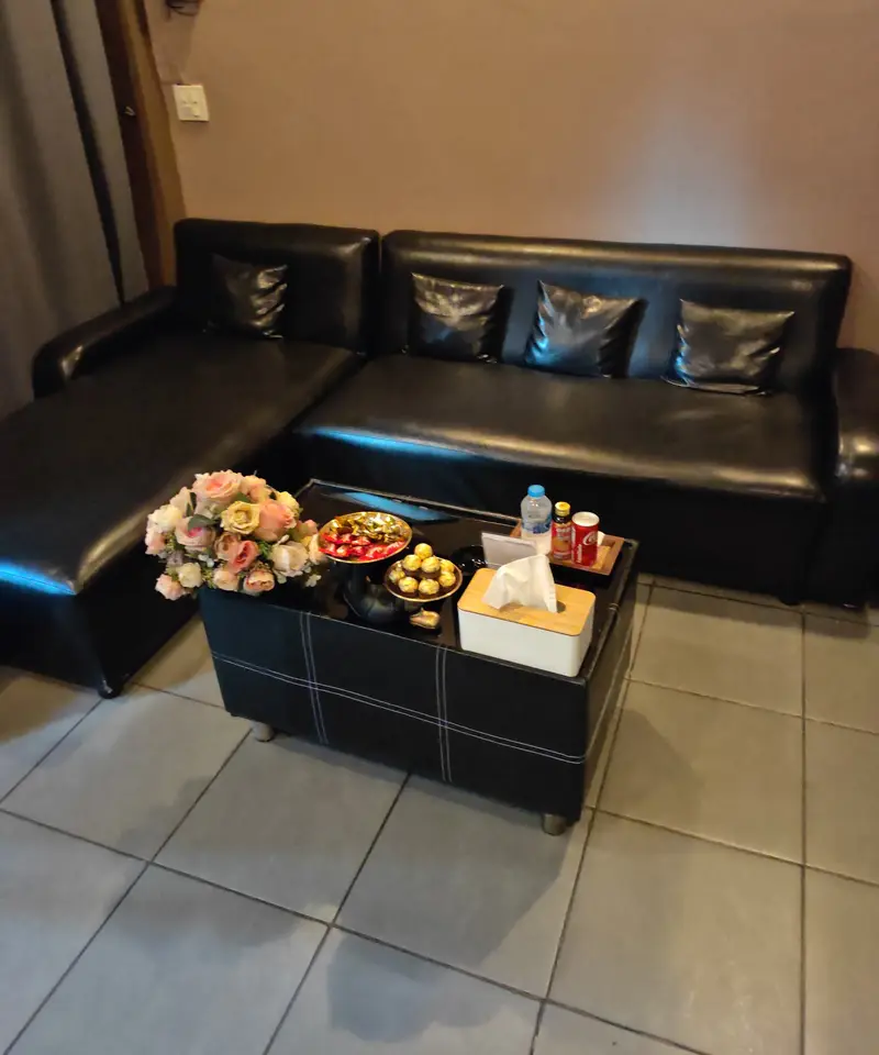 Black leather corner sofa and coffee table with flowers in the lounge